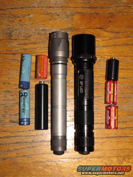 Two flashlights and assorted batteries on a wooden surface