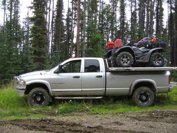2005 Dodge 3500 pickup truck parked on a dirt road with an ATV loaded in the bed