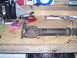 1991 Ford Bronco - A rusty driveshaft lies on a workbench next to tools and automotive parts.