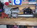 1991 Ford Bronco - A driveshaft rests on a wooden workbench alongside various tools and automotive fluids.