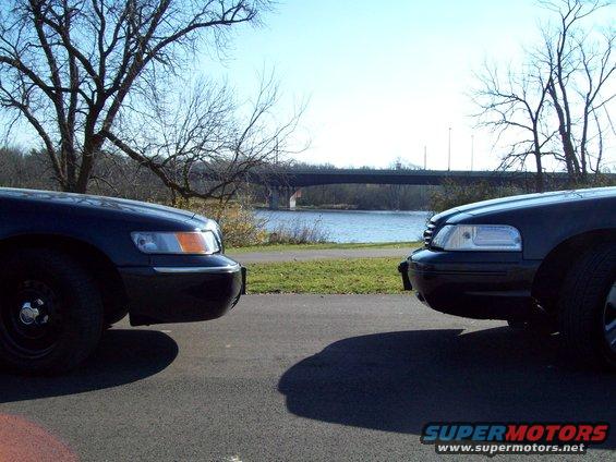 Two dark sedans, likely police cars, facing each other by a river
