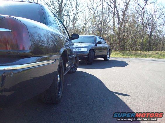 1999 Mercury Grand Marquis side view, dark color, parked next to another sedan