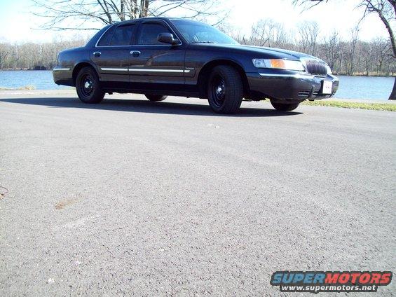 Dark 1999 Mercury Grand Marquis, 3/4 front view, parked by a lake
