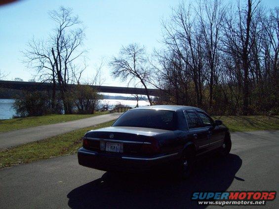 Dark sedan parked on asphalt, rear view. License plate reads MCM 6
