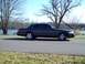 1999 Mercury Grand Marquis - Side view of a 1999 Mercury Grand Marquis parked outdoors with trees and water in the background.