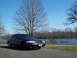 1999 Mercury Grand Marquis - A dark sedan is parked by a lake on a clear day, with bare trees and a picnic table visible.