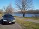 1999 Mercury Grand Marquis - Dark sedan parked on a paved path next to a body of water on a clear day.