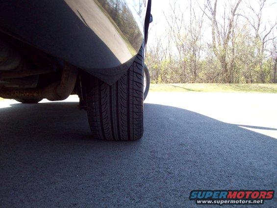 Rear tire and exhaust pipe of a dark-colored vehicle