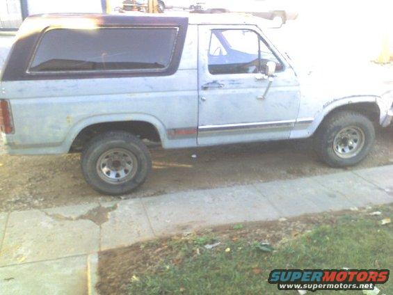 Light blue Ford Bronco with a black top, seen from the side