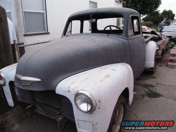Gray and white pickup truck with a chrome grille, missing its front bumper and grille insert