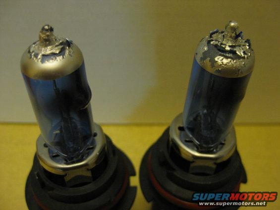 Two blue-tinted headlight bulbs with damaged tops sit on a yellow surface. Supermotors.net logo visible