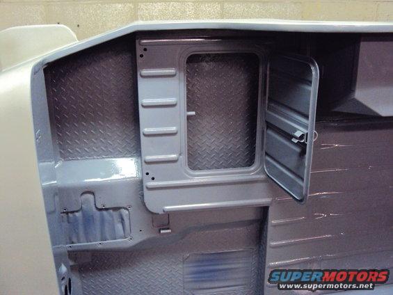 Gray painted vehicle interior with diamond plate flooring and a partially open compartment door