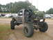 1984 Ford Bronco II - This heavily modified pickup truck, likely from the 1980s, is seen from the rear with a Christmas tree strapped to its bed.
