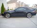 2001 Ford Mustang - Side view of a black convertible sports car with a black soft top and GT badging.