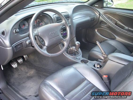 Black leather interior of a 2001 Ford Mustang, showing the dashboard, steering wheel, seats, and center console