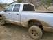 2005 Dodge 1500 - A muddy silver pickup truck drives off-road.