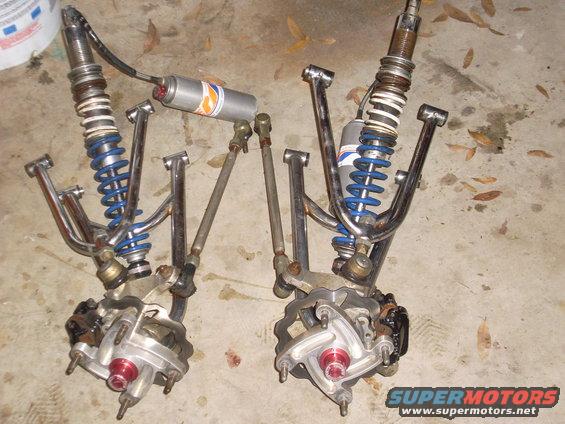 Two chrome A-arm suspension assemblies with blue coilover shocks and red hubs