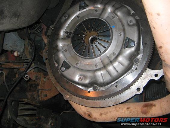Clutch assembly and flywheel with visible gear teeth, part of a vehicle's drivetrain