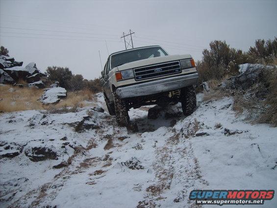 White Ford Bronco driving on a snowy, rocky trail