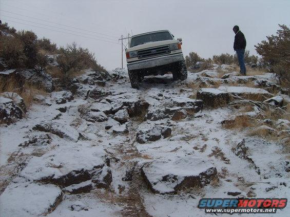 White 1989 Ford Bronco navigating a rocky, snow-covered trail