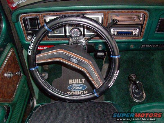 1978 Ford Bronco interior with green carpet, wood-grain trim, and a black steering wheel with "Choppers" text