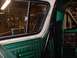 1978 Ford Bronco - Interior view of a green vehicle, with a roll cage and reflections of music memorabilia in the window.