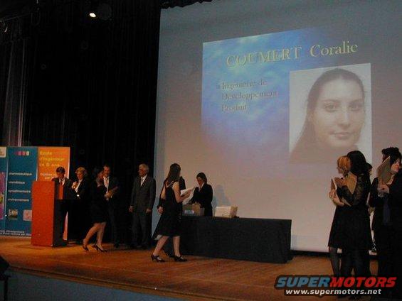 People on a stage with a projection screen displaying a name and photo