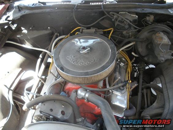 Engine bay showing Edelbrock air cleaner, red engine block, and yellow spark plug wires