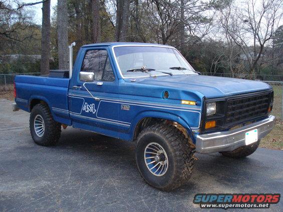 Blue 1985 Ford F-150 pickup truck with 4x4 decals and aftermarket wheels