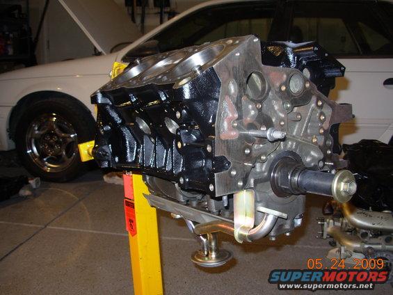 Engine block on stand, white car in background