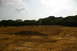 1986 Ford Bronco - A wide view of a cleared and graded area, possibly for construction, with distant structures and trees under a cloudy sky.