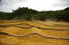 1986 Ford Bronco - RC car track with dirt mounds and black hose borders under a cloudy sky.