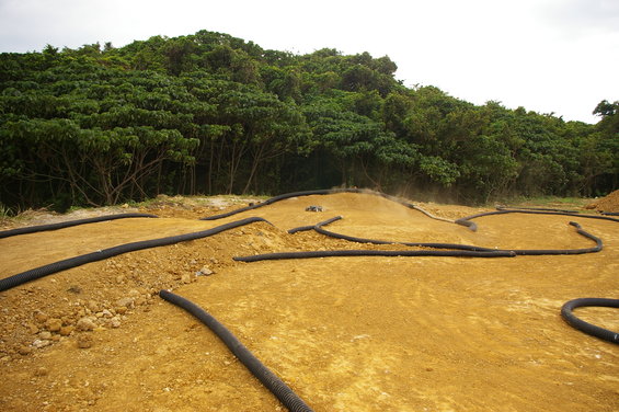 RC car on a dirt track with black tubing borders, trees in background