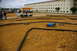 1986 Ford Bronco - Remote control cars race on a dirt track in front of a large building.