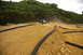 1986 Ford Bronco - A remote controlled car leaps over a dirt track obstacle, kicking up dust.