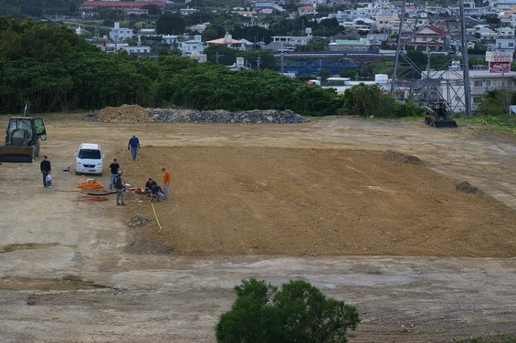 Construction site with a tractor, a white van, and a small skid steer loader