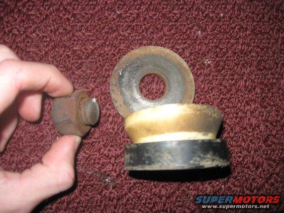 hand holding rusty bolt next to suspension bump stop and washer