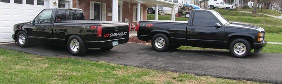 Two black Chevrolet C/K pickup trucks parked on a driveway, one with a tonneau cover