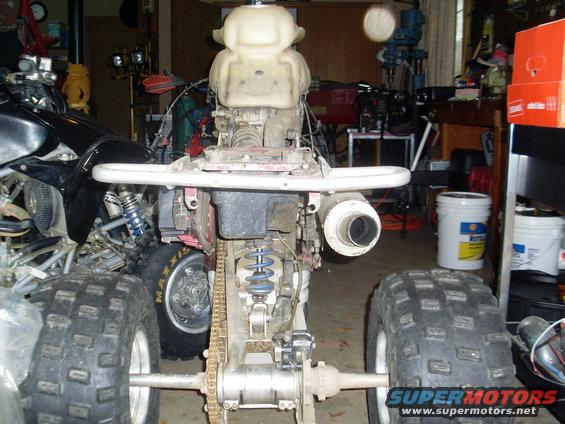 Rear view of disassembled ATV with prominent exhaust and chain drive