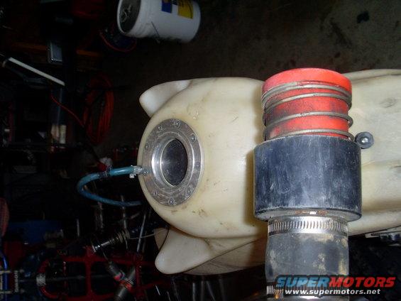 Plastic fuel tank with metal fill cap and red-capped intake hose attached