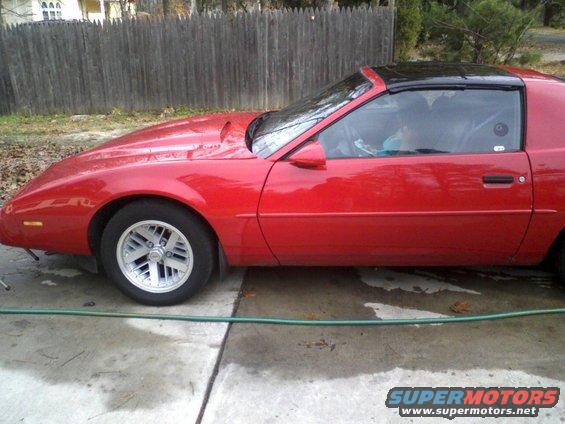 Red 1985 Pontiac Firebird side view with black T-top roof and aftermarket hood scoop