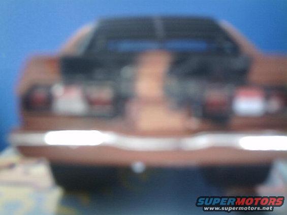 Rear of a brown car with horizontal taillights and chrome bumper