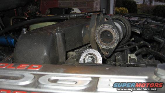 Engine bay with manifold removed, showing internal components and hoses. Text on metal reads 'COOLED'