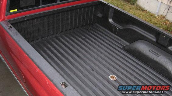 Red pickup truck bed with black liner and visible gooseneck hitch