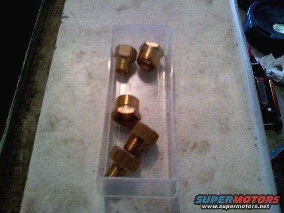Several brass fittings in a clear plastic case on a workbench