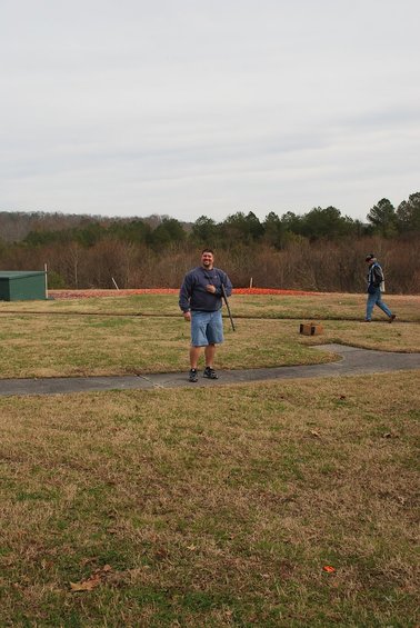 Man holding a rifle at a shooting range with another person in the background