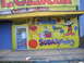 1991 Ford Bronco - A brightly painted storefront displays cartoon characters and advertisements for piñatas, balloons, and cold sodas.