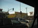 1991 Ford Bronco - View from a vehicle looking towards a street scene with several cars and a large yellow building displaying various advertisements.
