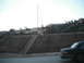 1991 Ford Bronco - A dark sedan is captured in motion, viewed from the rear, with a blurred hillside and buildings in the background.