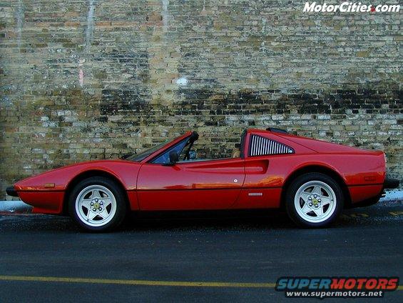 red Ferrari parked by brick wall